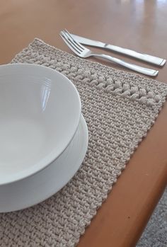 a white bowl sitting on top of a wooden table next to a fork and knife