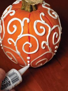 an orange painted pumpkin sitting on top of a wooden table next to a white marker