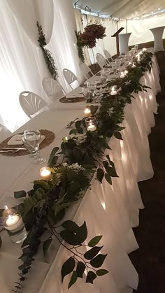 a long table with candles and greenery on it is set up for an event