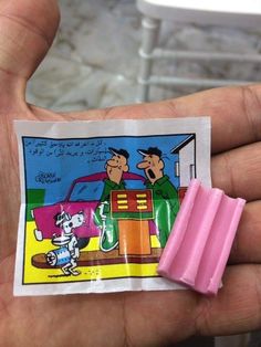 a hand holding a small pink eraser with a cartoon on it's side