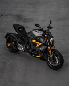 a black and yellow motorcycle parked in a parking lot next to some concrete flooring