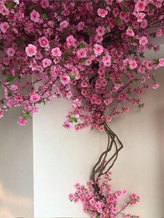 a vase with pink flowers in it sitting on a table next to a white wall