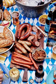 there are many sausages on the table with beer and other food items around it