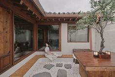 a woman sitting on the ground in front of a house with an outdoor living area