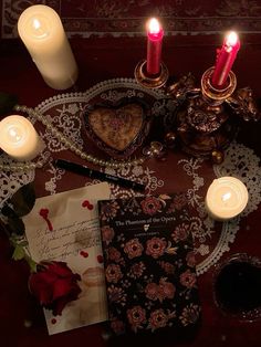 a table topped with candles next to a heart shaped card and other items on top of it