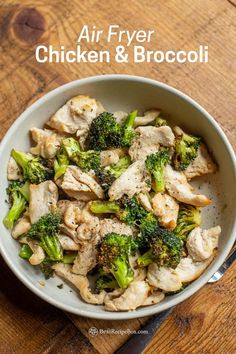 a bowl filled with chicken and broccoli on top of a wooden table