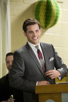 a man in a suit and tie smiling at the camera