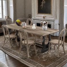 a dining room table and chairs in front of an ornate fireplace with paintings on the wall