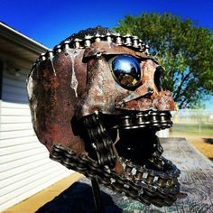 an old metal mask is sitting on top of a wooden table in front of a house