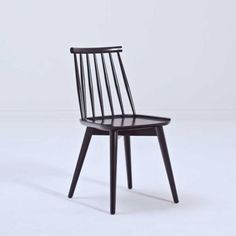 a black wooden chair on a white floor with no one in the room behind it