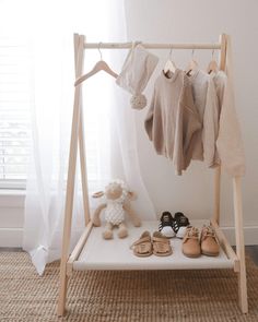 a baby's clothes rack with shoes and toys on it in front of a window