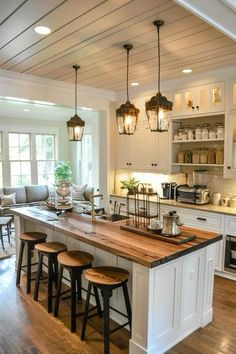 a kitchen island with stools and lights hanging from it's ceiling over the counter