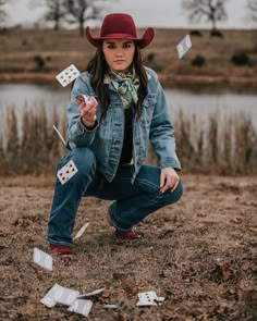 a woman in a cowboy hat and jeans is playing with dices on the ground