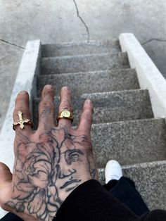 a person with tattoos on their hand standing next to some stairs