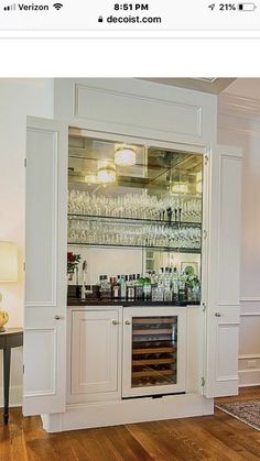 an image of a home bar with wine glasses on the shelves and bottles behind it