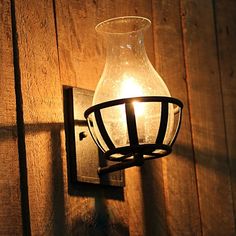 a light that is on the wall next to a wooden paneled wall with a metal cage around it