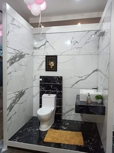 a white toilet sitting inside of a bathroom next to a sink and bathtub covered in black marble