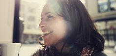 a woman smiling and holding a coffee cup