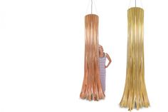 a woman is standing next to two tall wooden lamps that are shaped like long strips of wood