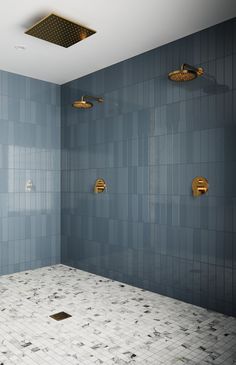 an empty bathroom with blue tile and gold faucets on the shower head wall