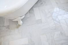 a white bath tub sitting on top of a bathroom floor next to a tiled floor