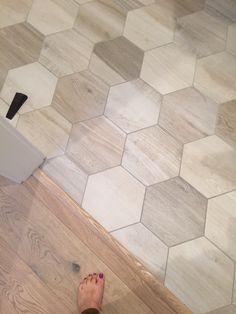 a person standing on the floor with their feet up next to an object that looks like hexagonal tiles