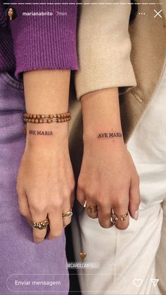 two people holding hands with tattoos on their wrists and the words are written in different languages