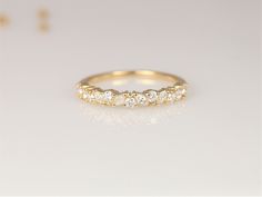 a yellow gold wedding band with five round brilliant cut diamonds set in the middle, on a white background