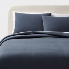 a bed with blue sheets and pillows on it