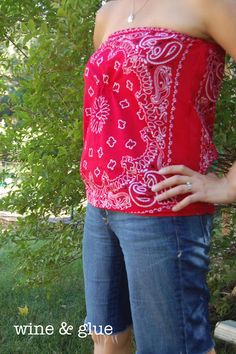 a woman standing in front of a tree wearing jeans and a red top