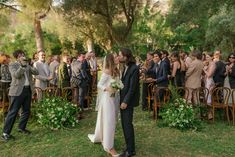 a bride and groom kiss as they walk down the aisle at their outdoor wedding ceremony