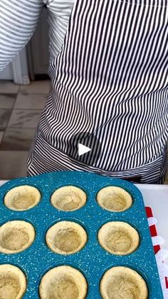 a blue tray filled with muffins sitting on top of a counter next to a person