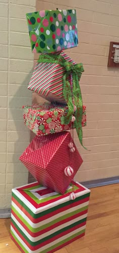 a stack of wrapped presents sitting on top of a hard wood floor next to a brick wall