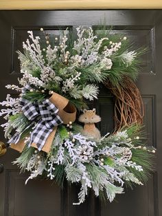 a wreath on the front door decorated with pine cones, evergreens and white berries