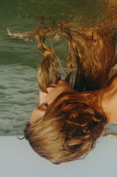 a woman floating in the water with her hair blowing back