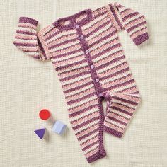 a baby's pink and purple striped knitted outfit laying on top of a white blanket