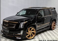 a black suv with gold rims is parked in a checkered floored area