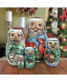 a wooden table topped with nesting dolls and a christmas tree in the backround