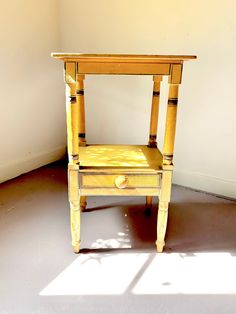 a small wooden table with a drawer on it's side in an empty room