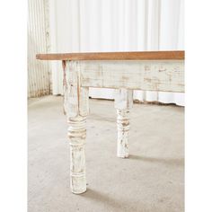 an old white table with wood top and legs in the middle of carpeted room