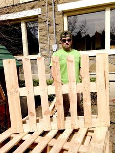 a man standing in front of a pile of wooden pallets with sunglasses on his face