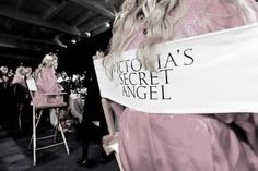 a woman in a pink dress is holding a sign that says victoria's secret angel