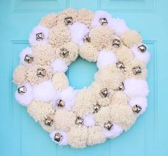 a white wreath with bells hanging on a blue door