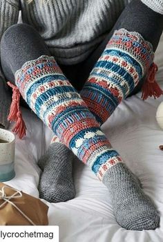 a woman sitting on top of a bed with her legs crossed and wearing knitted socks