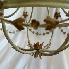 a chandelier hanging from the ceiling with flowers on it's arms and leaves