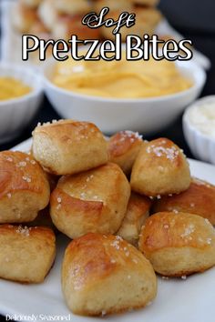 several small pastries on a white plate next to bowls of dips and cheese