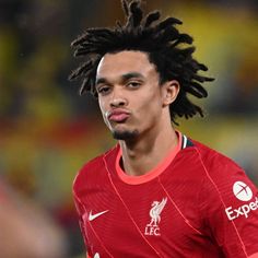 a young man with dreadlocks on his head in a soccer uniform looking at the camera