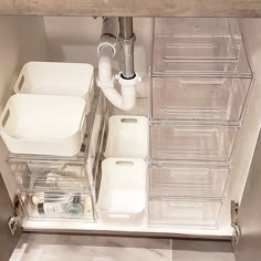 an organized bathroom with clear drawers and toiletries on the bottom shelf is pictured in this image