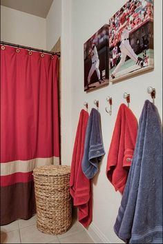 a bathroom with towels hanging on the wall and two pictures above the shower curtain that has baseball players on it