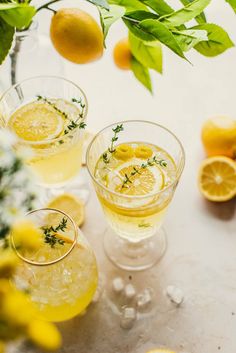 three glasses filled with lemonade and garnished with herbs